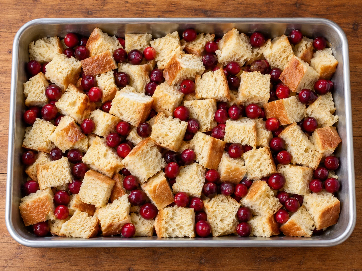 Cubed bread and fresh cranberries layered in the baking pan before adding custard