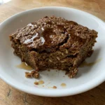 A slice of warm gingerbread baked oatmeal on a white ceramic plate.